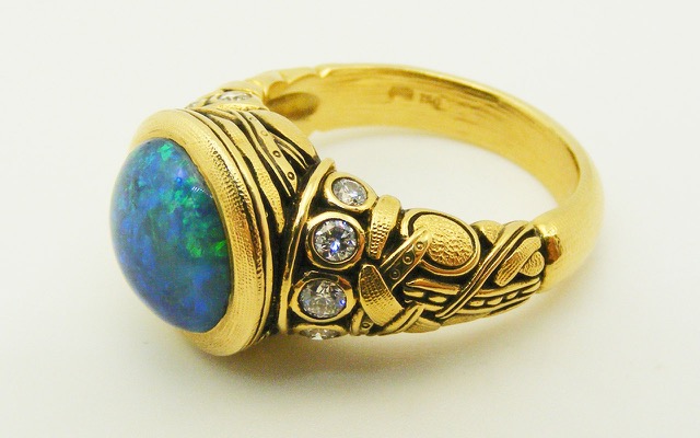 R-58 
“Reed” black opal ring, 18K yellow gold, 3.33 ct black opal center gemstone, 10 side diamonds totaling 0.28 ctw.
Available for immediate delivery in finger size 6 ¾.  
$11,200
