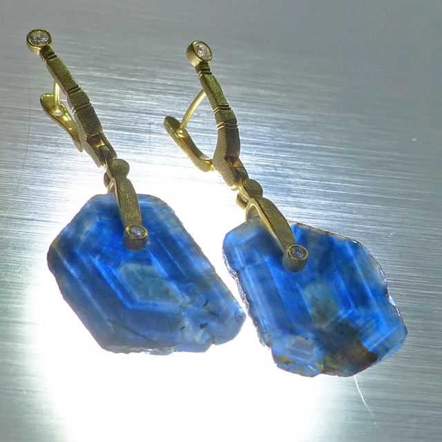 E167MD
“Sticks & Stones”  earrings in 18K yellow gold with blue sapphire slice drops and 4 diamonds totaling 0.17 ct.  These are polished cross-sections of a large blue sapphire crystal that retain the natural shape and rustic surface of the crystal around the edge. The slightly chatoyant patterns in the slices reveal the crystal structure! 23.37 cts total weight.
Immediate delivery
$3,275

